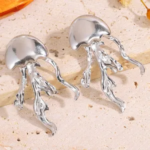 Détail de boucles d'oreilles méduses en argent avec tentacules ondulés sur pierre texturée