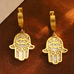 Detailaufnahme goldener Hamsa-Hand-Ohrringe mit weißer Muscheleinlage für Damen