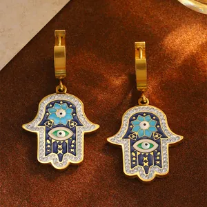 Details von goldenen Hamsa-Hand-Ohrringen mit blauem Bösen Blick und Zirkonia