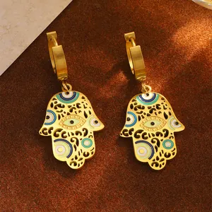 Makroaufnahme von Hamsa Hand Ohrringen in Gold mit blauem Evil Eye Emaille-Detail