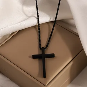 Minimalist black stainless steel cross necklace displayed on luxury jewelry box and silk