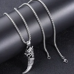 Macro shot of silver dragon head tooth pendant with vintage texture on a stainless steel chain