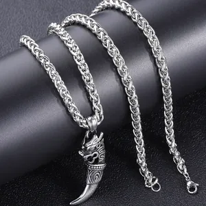 Macro detail of men's hip hop wolf tooth dragon pendant and wheat woven steel chain