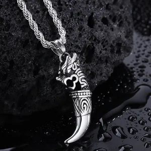 Detail of silver wolf tooth pendant with dragon carving and twisted rope chain