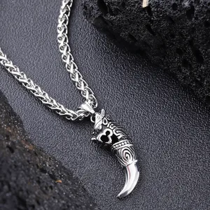 Detailed view of men's wolf tooth pendant with oxidized wolf head engraving on wheat chain