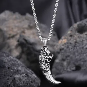 Detail of silver wolf tooth pendant with dragon head on black volcanic rock