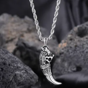Macro detail of silver dragon head wolf tooth pendant on dark volcanic rock background