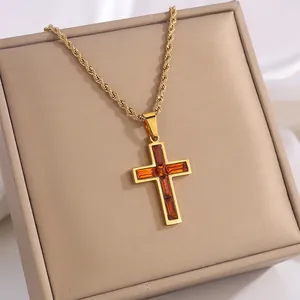 Detail eines Vintage-Kreuzanhängers in Gold mit Bernstein-Edelstein an einer Seilkette