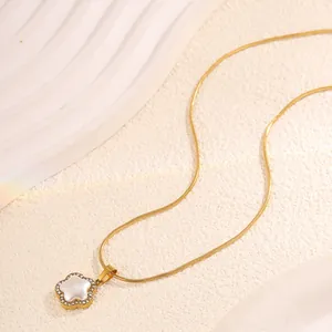 Détail macro du pendentif fleur dorée avec incrustation de nacre et bords en zircon