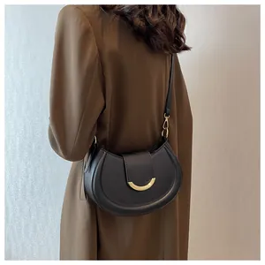 Fashionable black crescent shoulder bag with golden buckle shown on model in street style