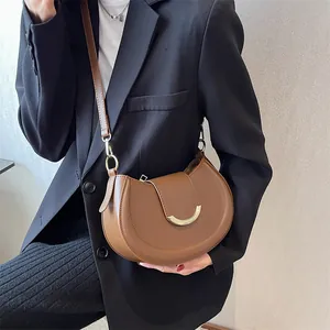 Detailed view of a brown crescent shoulder bag worn with a black blazer for styling