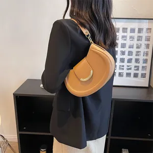 Detail of caramel crescent shoulder bag with smooth leather and gold hardware on model