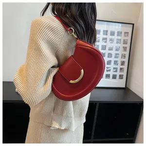 Detail showing red crescent shoulder bag with gold clasp on a model shoulder