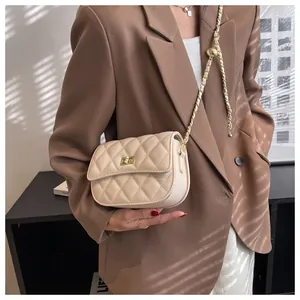 Detail van beige gewatteerde crossbodytas met een gouden balketting en draaisluiting