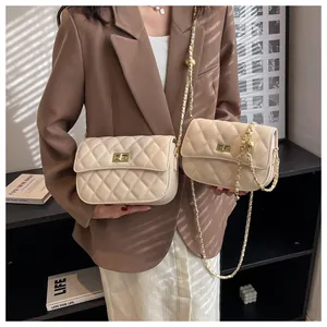 Detail van beige gewatteerde crossbodytas met gouden draaisluiting en metalen kettingriem