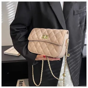 Detailopname van beige gewatteerde crossbodytas met gouden draaisluiting en ketting