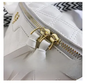 Detail of white quilted bag showing smooth golden double zippers and fine leather texture