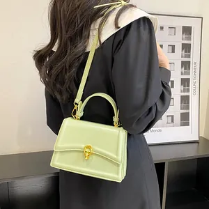 Detail van de muntgroene leren crossbodytas met gouden sluiting gedragen door model