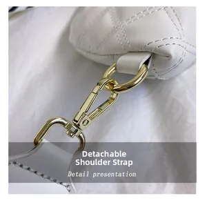 Detail of detachable shoulder strap with golden metal hook on white quilted bag