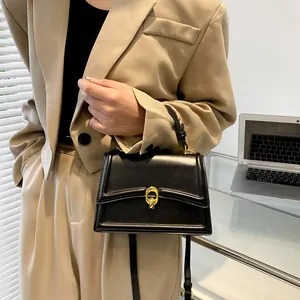 Elegante zwarte leren handtas met gouden sluiting in een professionele kantooromgeving