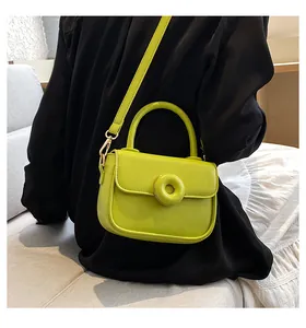 Detail of neon green handbag featuring a circular ring buckle and smooth faux leather