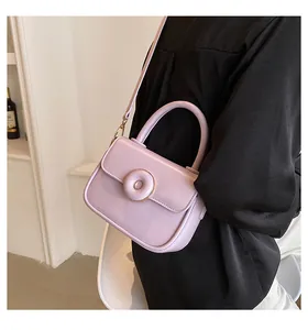 Side view of a lavender patent leather mini crossbody bag with a round buckle on black outfit
