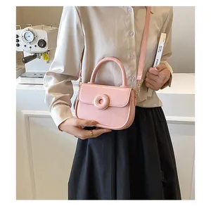 Close-up of pink leather handbag featuring a unique 3D round buckle in a cozy cafe setting