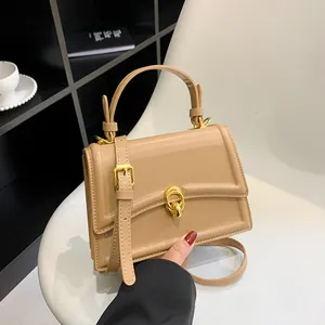 Kaki vierkante handtas met gouden gespen en verstelbare riem op een witte stoel