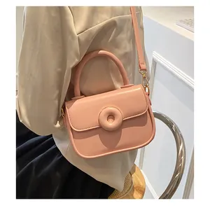 Detailed view of pink crossbody bag with round handle and metallic hardware on a model