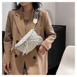 White quilted belt bag with geometric strap and fringe detail worn on a model