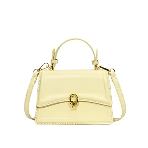 Elegante lichtgele crossbody handtas met gouden gesp en leren riem op witte achtergrond