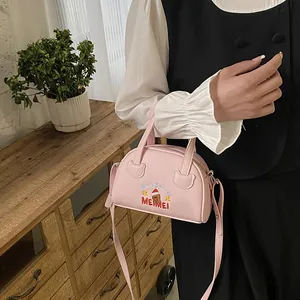 Pink crossbody bag with Christmas bear embroidery shown in a warm lifestyle setting