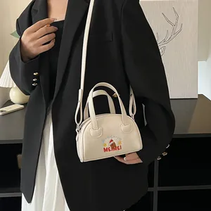 Chic cream mini crossbody bag with festive bear embroidery shown on model in black suit