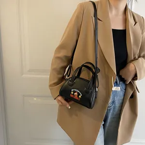 Detail view of a black mini Boston bag with Christmas embroidery on a brown blazer