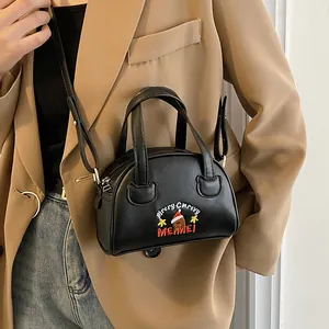 Close-up of black mini Boston bag with bear embroidery worn by a model in a suit