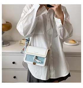 Dettaglio dell'elegante borsa a tracolla bicolore con trama intrecciata e foulard