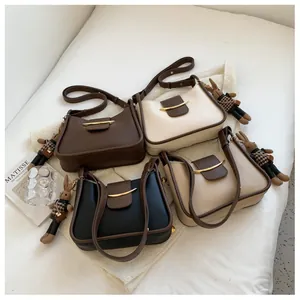Detail van tweekleurige crossbodytassen met maanvormige gouden gesp en konijn hanger