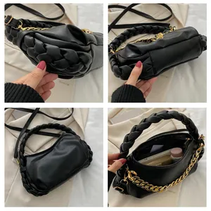 Detail of black crossbody bag with woven handle, gold chain and interior storage