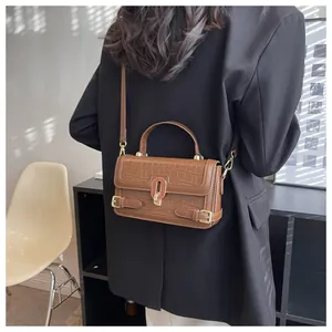 Dettaglio borsa in pelle coccodrillo marrone con chiusura dorata e particolare a forma di U