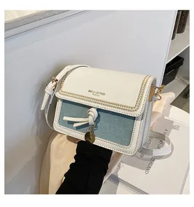 Dettaglio borsa a tracolla blu e bianca con testo SMN & LEATHER e ciondolo in metallo