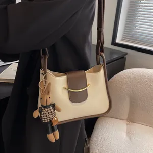 Minimalistische schoudertas met kleurvlakken, konijnenhanger en gouden gesp