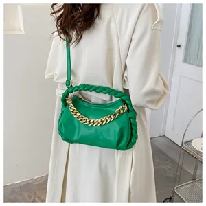 Detail of vibrant green PU leather crossbody bag with gold chain and woven handle