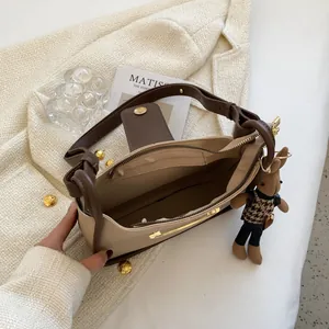 Beige en bruine lederen schoudertas met schattige konijntjes hanger en ruim interieur