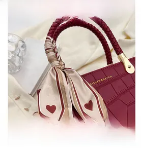 Macro view of wine red crocodile embossed texture with red woven handle and silk scarf