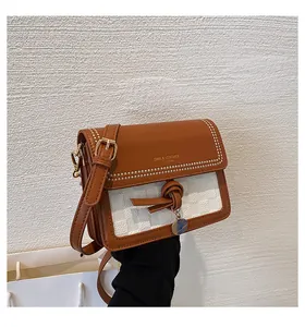 Dettaglio del nodo in pelle caramello e del ciondolo circolare su una borsa a tracolla