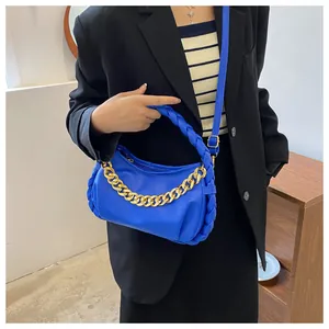 Detail of bright blue leather handbag with matte gold chain and woven handle accent