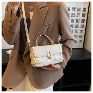 Dettaglio borsa crema effetto coccodrillo con chiusura dorata su un blazer marrone