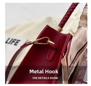 Detail of red wedding handbag featuring gold metal hook and floral silk scarf handle