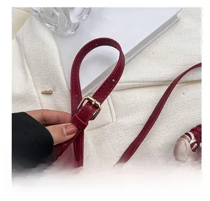 Detail of wine red leather strap with gold buckle and silk scarf handle accent