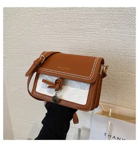 Dettaglio della borsa a tracolla in pelle caramello con pannello intrecciato e borchie